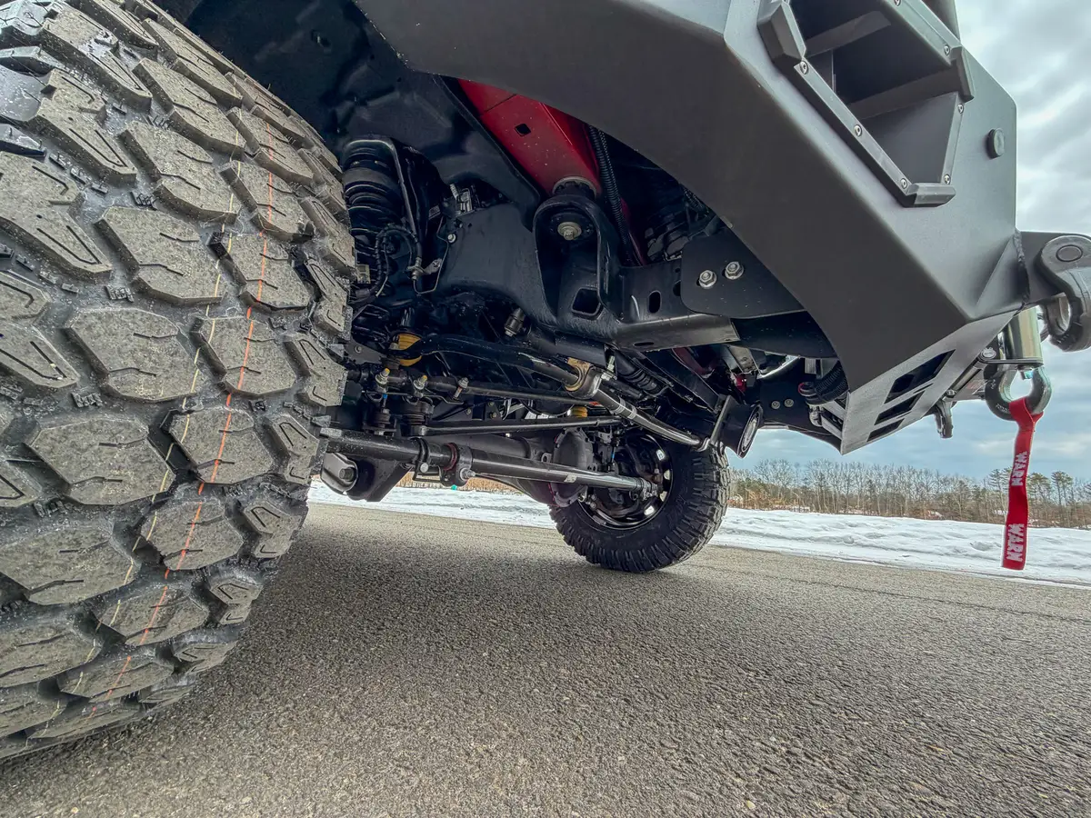 Front axle and tire tread close-up from low angle.